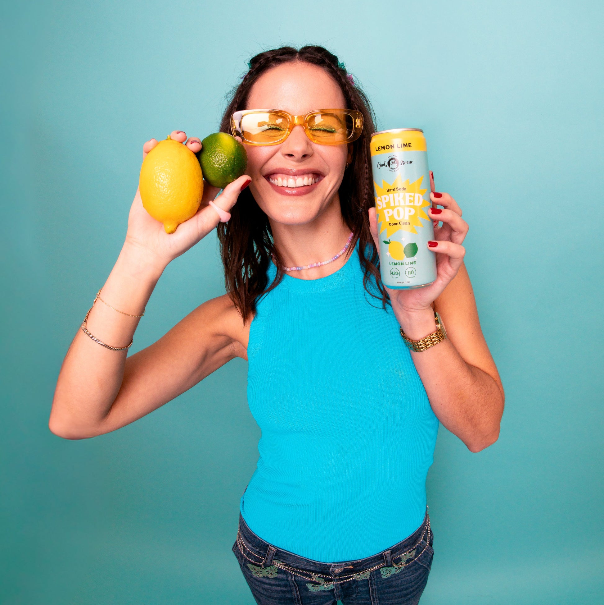 Woman holding a can and a lemon against a teal background