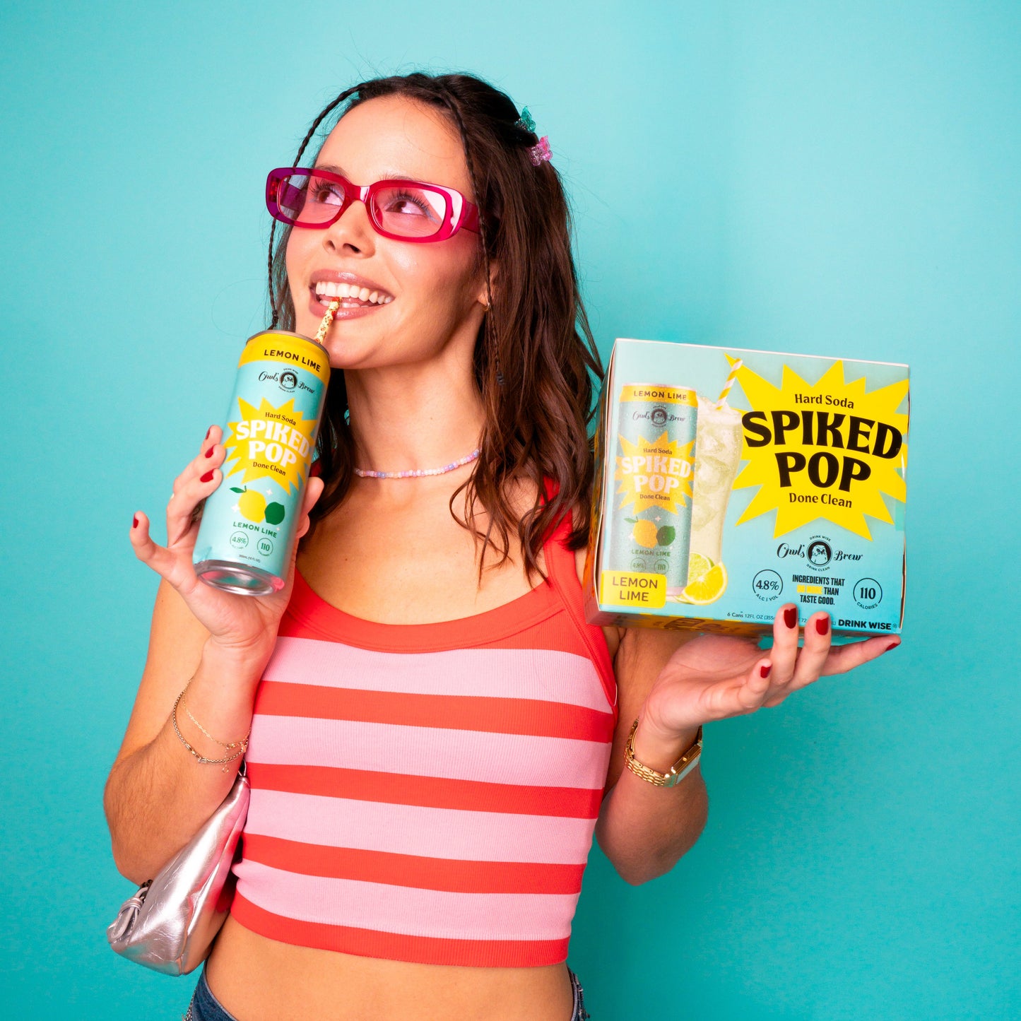 Woman holding a drink and a box of 'Spiked Pop' against a teal background